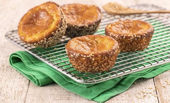 Foto da receita de Muffin Funcional. Observa-se quatro muffins desenformados dispostos sobre uma grade, que está em cima de um guardanapo verde. Atrás, uma pequena colher de madeira.